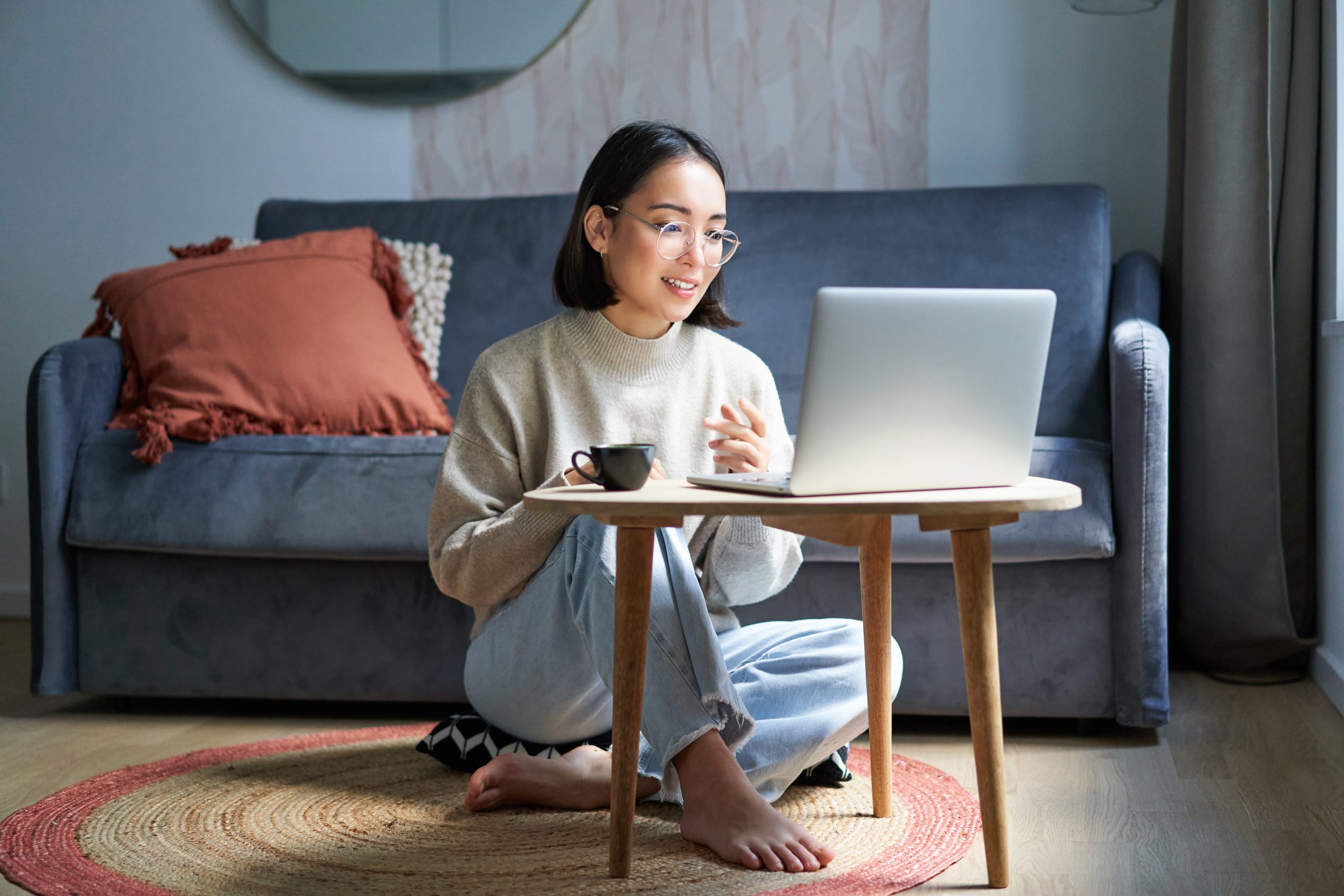 Portrait of beautiful young woman professional, working on remote from home, freelancing with her laptop, video chats, drinks coffee.